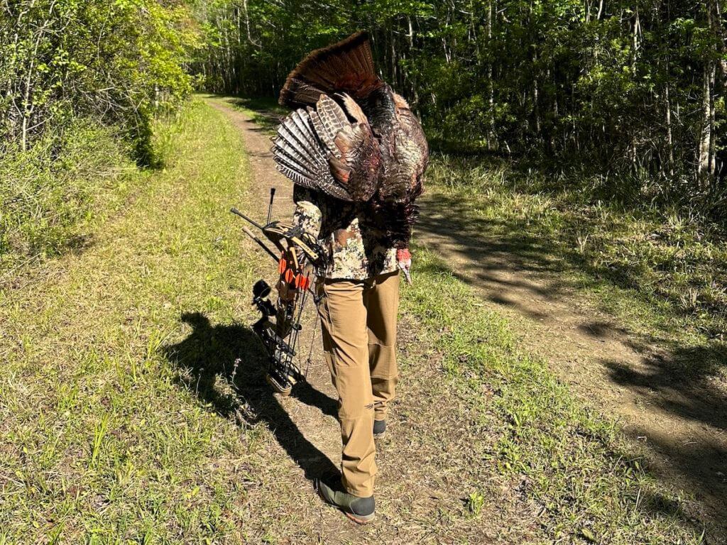 Bow hunter wearing Sitka Equinox Guard Line and toting a turkey